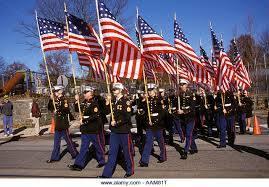 Uniformed individuals marching with an American flag